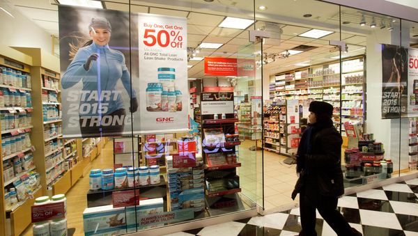 A woman walks past a GNC store in New York - Sputnik International