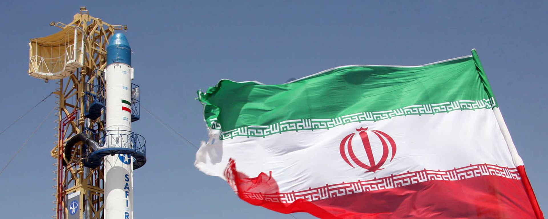 Iranian flag fluttering in front of Iran's Safir Omid rocket, which is capable of carrying a satellite into orbit, before it's launch in a space station at an undisclosed location in the Islamic republic Iranian flag fluttering in front of Iran's Safir Omid rocket, which is capable of carrying a satellite into orbit, before it's launch in a space station at an undisclosed location in the Islamic republic - Sputnik International, 1920, 13.12.2021
