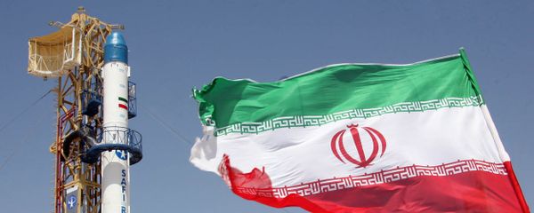 Iranian flag fluttering in front of Iran's Safir Omid rocket, which is capable of carrying a satellite into orbit, before it's launch in a space station at an undisclosed location in the Islamic republic - Sputnik International