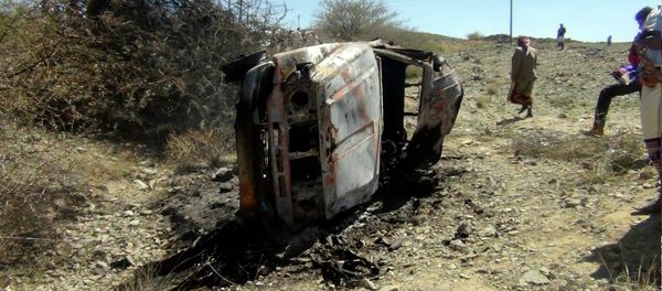 People gather near a destroyed car that was carrying militants in the Sawmaa area of al-Bayda province, Yemen, Saturday, April 19, 2014. A Yemeni military official says an American drone strike has killed nine suspected al-Qaida militants and inadvertently killed and wounded some civilians. - Sputnik International