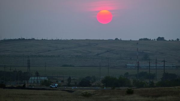 A police car moves in an emptied field about 28 kilometers (17 miles) from the Ukrainian border, near Kamensk-Shakhtinsky, Rostov-on-Don region, Russia, during sunset at Friday, Aug. 22, 2014 - Sputnik International