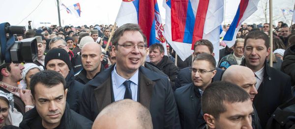 Kosovo Serbs gather holding up their national flag as they welcome Serbian Prime Minister Aleksandar Vucic, surrounded by body guards, to the village of Pasjane, during his visit to Kosovo. - Sputnik International
