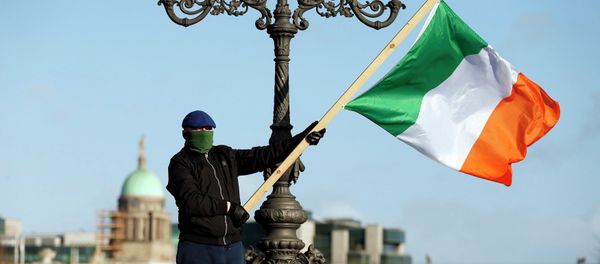 A demonstrator waves the national flag as people gather to protest against austerity policies and increases in water bills, according to local media, in central Dublin A demonstrator waves the national flag as people gather to protest against austerity policies and increases in water bills, according to local media, in central Dublin - Sputnik International