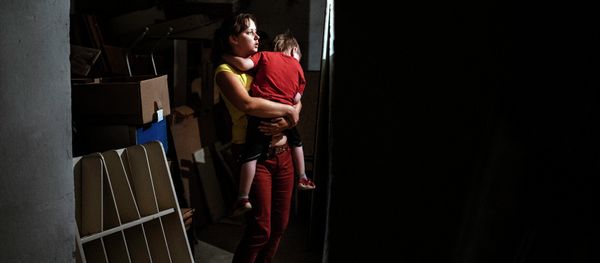 A woman holds her child in her arms as they are hidding in a bomb shelter in an orphanage during a shelling in the town of Makiyivka on August 19, 2014 - Sputnik International