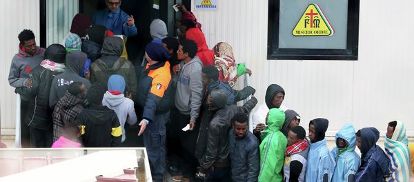 Migrants stand in front of the infirmary at the immigration centre on the southern Italian island of Lampedusa - Sputnik International