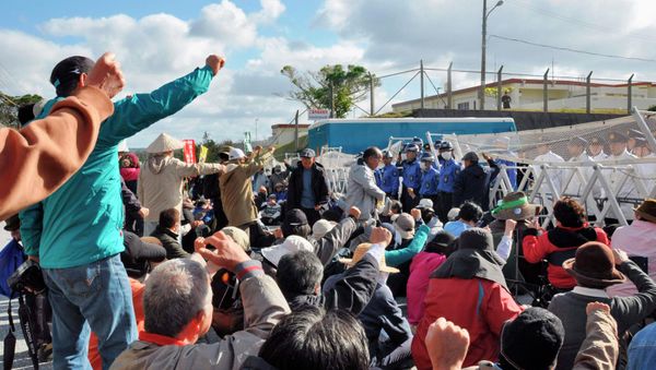 Anti-base activists raise their fists in front of a gate of the U.S. Marine Corps' Camp Schwab at the tiny hamlet of Henoko in Nago on the southern Japanese island of Okinawa, January 15, 2015 - Sputnik International