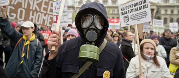 An anti-fracking demonstrator wears a gas mask and holds flowers during a protest in Bucharest, Romania, Sunday, April 6, 2014 - Sputnik International