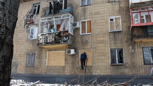 A man covers windows in a building which was damaged by shelling in Donetsk A man covers windows in a building which was damaged by shelling in Donetsk - Sputnik International