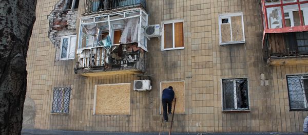 A man covers windows in a building which was damaged by shelling in Donetsk A man covers windows in a building which was damaged by shelling in Donetsk - Sputnik International