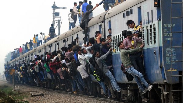 Indian passengers stand and hang onto a train as it departs from a station on the outskirts of New Delhi on February 25, 2015 Indian passengers stand and hang onto a train as it departs from a station on the outskirts of New Delhi on February 25, 2015 - Sputnik International