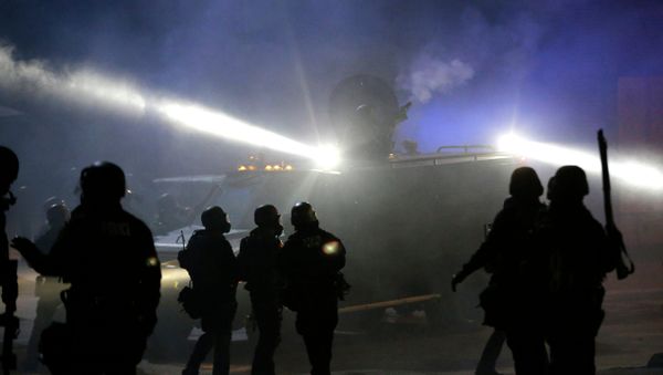 Police in riot gear stand around an armored vehicle as smoke fills the streets Tuesday, Nov. 25, 2014, in Ferguson, Mo. Police in riot gear stand around an armored vehicle as smoke fills the streets Tuesday, Nov. 25, 2014, in Ferguson, Mo. - Sputnik International