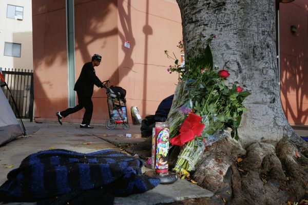 A pedestrian walks past flowers and candles placed on a sidewalk near where a man was shot and killed by police in the Skid Row section of downtown Los Angeles - Sputnik International