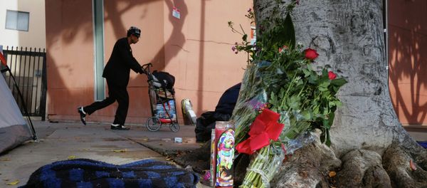 A pedestrian walks past flowers and candles placed on a sidewalk near where a man was shot and killed by police in the Skid Row section of downtown Los Angeles A pedestrian walks past flowers and candles placed on a sidewalk near where a man was shot and killed by police in the Skid Row section of downtown Los Angeles - Sputnik International