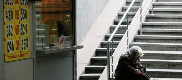 A woman sits next a currency exchange office in Kiev February 26, 2015 - Sputnik International
