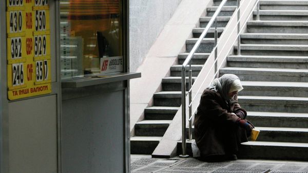 A woman sits next a currency exchange office in Kiev February 26, 2015 - Sputnik International
