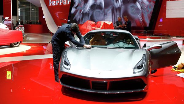 An employee cleans a Ferrari car ahead of the 85th International Motor Show in Geneva, March 2, 2015 - Sputnik International