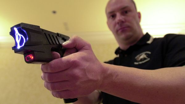 Clay Winn, of TASER International, demonstrates the company's Advanced M-26 model during a news conference in Las Vegas - Sputnik International