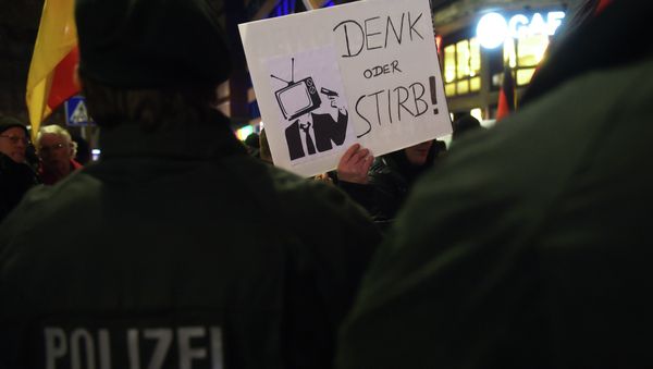 A sympathizer of Duegida, a local copycat of Dresden's right-wing populist movement PEGIDA (Patriotic Europeans Against the Islamisation of the Occident) holds up a placard reading 'Think or die!' in Duesseldorf, western Germany on February 2, 2015 A sympathizer of Duegida, a local copycat of Dresden's right-wing populist movement PEGIDA (Patriotic Europeans Against the Islamisation of the Occident) holds up a placard reading 'Think or die!' in Duesseldorf, western Germany on February 2, 2015 - Sputnik International