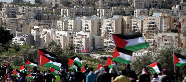 Palestinian protestors walk with their national flag during a demonstration on a hill in the West Bank village of Bilin in front of the Israeli settlement of Modiin Illit (background) on February 27, 2015 - Sputnik International