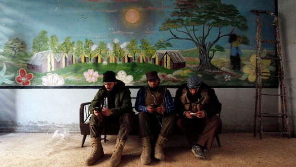 Rebel fighters of 'Al-Sultan Murad' brigade use their mobile phones inside a room near the frontline in Handarat area, north of Aleppo March 1, 2015 - Sputnik International