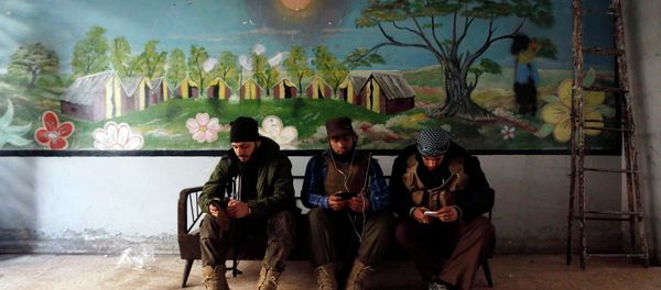 Rebel fighters of 'Al-Sultan Murad' brigade use their mobile phones inside a room near the frontline in Handarat area, north of Aleppo March 1, 2015 Rebel fighters of 'Al-Sultan Murad' brigade use their mobile phones inside a room near the frontline in Handarat area, north of Aleppo March 1, 2015 - Sputnik International
