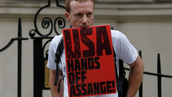 A supporter of WikiLeaks founder Julian Assange holds on to a placard with his teeth during a June vigil outside the Ecuadorian Embassy in London to mark Assange's two years in refuge at the embassy. A supporter of WikiLeaks founder Julian Assange holds on to a placard with his teeth during a June vigil outside the Ecuadorian Embassy in London to mark Assange's two years in refuge at the embassy. - Sputnik International