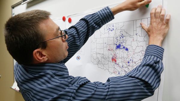 June 26, 2014 file photo, Austin Holland, research seismologist at the Oklahoma Geological Survey, hangs up a chart depicting earthquake activity at their offices at the University of Oklahoma in Norman, Okla - Sputnik International