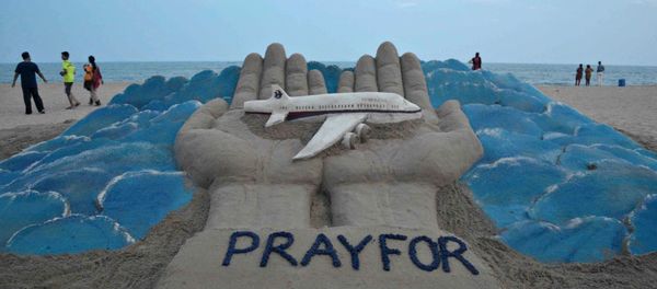 Beachgoers walk past a sand sculpture made by Indian sand artist Sudersan Pattnaik with a message of prayers for the missing Malaysian Airlines flight MH370 - Sputnik International