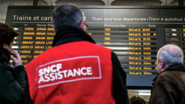 People stand next to a member of SNCF customer service staff in front of a board displaying departure information indicating that all trains have been delayed at Lyon-Part-Dieu railway station in Lyon People stand next to a member of SNCF customer service staff in front of a board displaying departure information indicating that all trains have been delayed at Lyon-Part-Dieu railway station in Lyon - Sputnik International