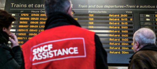 People stand next to a member of SNCF customer service staff in front of a board displaying departure information indicating that all trains have been delayed at Lyon-Part-Dieu railway station in Lyon People stand next to a member of SNCF customer service staff in front of a board displaying departure information indicating that all trains have been delayed at Lyon-Part-Dieu railway station in Lyon - Sputnik International