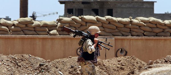 A Kurdish Peshmerga fighter carries his weapon walks onto his base, where two flags of the Islamic State in Iraq and the Levant (ISIL) are seen on a building, right, and water tower, left, at the front line with the al-Qaida-inspired militants in Tuz Khormato, 100 kilometers (62 miles) south of the oil rich province of Kirkuk, northern Iraq. A Kurdish Peshmerga fighter carries his weapon walks onto his base, where two flags of the Islamic State in Iraq and the Levant (ISIL) are seen on a building, right, and water tower, left, at the front line with the al-Qaida-inspired militants in Tuz Khormato, 100 kilometers (62 miles) south of the oil rich province of Kirkuk, northern Iraq. - Sputnik International