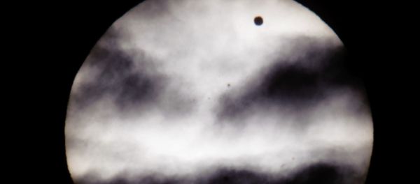 The larger black dot, top right, is the planet Venus as it transits across the face of the Sun as viewed from Earth in Budapest, Hungary - Sputnik International
