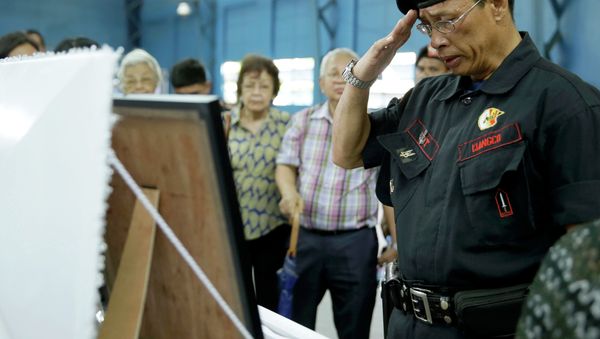A Philippine National Police officer salutes before the flag-draped coffin of one of the 44 commandos killed in a January clash with Muslim rebels. - Sputnik International