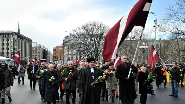 People carry Latvian flags as they march to the Freedom Monument to commemorate World War II veterans who fought in Waffen SS divisions, in Riga, Latvia, Sunday, March 16, 2014 - Sputnik International