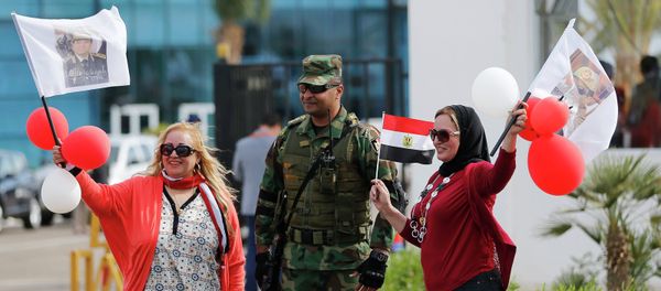 Egyptian women wave flags with pictures of Egyptian President Abdel Fattah al-Sisi, next to a soldier outside a conference centre hosting the Egypt Economic Development Conference (EEDC) in Sharm el-Sheikh, in the South Sinai governorate, south of Cairo, March 14, 2015 Egyptian women wave flags with pictures of Egyptian President Abdel Fattah al-Sisi, next to a soldier outside a conference centre hosting the Egypt Economic Development Conference (EEDC) in Sharm el-Sheikh, in the South Sinai governorate, south of Cairo, March 14, 2015 - Sputnik International