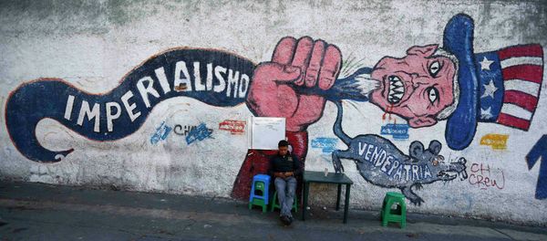 A man sits next to graffti, which reads imperialism and traitor, in Caracas March 9, 2015 - Sputnik International