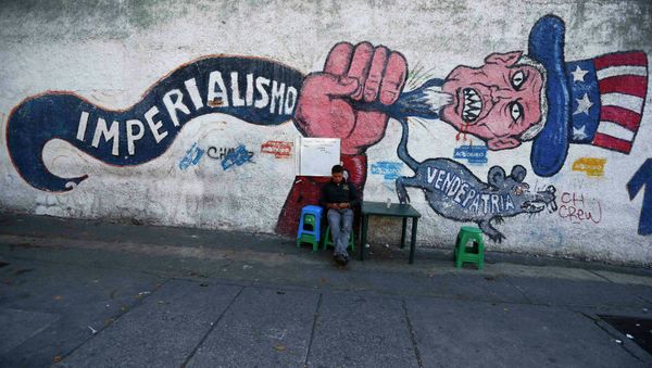 A man sits next to graffti, which reads imperialism and traitor, in Caracas March 9, 2015 - Sputnik International