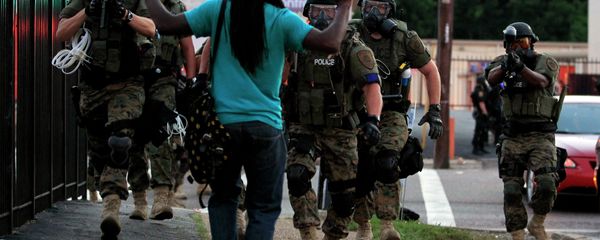 In this Aug. 11, 2014, file photo, police wearing riot gear walk toward a man with his hands raised Monday, Aug. 11, 2014, in Ferguson - Sputnik International