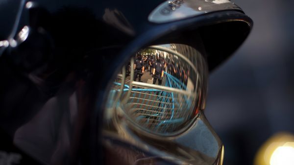 Riot police officers behind barricades are seen reflected on a safety glasses of a protester firefighter as they cordon off the road to block the access of demonstrators during a protest in Madrid, Spain - Sputnik International