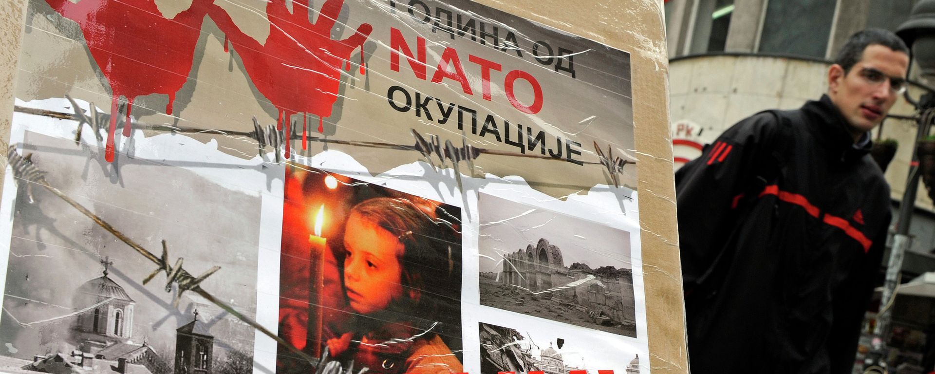 A man walks past a poster with the reading “Ten years of NATO occupation of Serbia”, and displaying images from 1999 NATO air campaign against Serbia and Montenegro, in Belgrade on March 23, 2009.  - Sputnik International, 1920, 24.03.2022