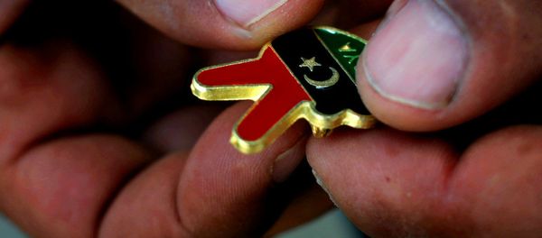 A Libyan man holds a souvenir of the Libyan revolution in the colors of the pre-Gadhafi flag A Libyan man holds a souvenir of the Libyan revolution in the colors of the pre-Gadhafi flag - Sputnik International