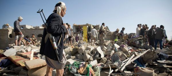 A Houthi Shiite fighter stand guard as people search for survivors under the rubble of houses destroyed by Saudi airstrikes near Sanaa Airport, Yemen - Sputnik International