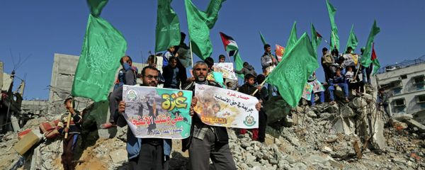 Palestinian Hamas supporters wave Hamas flags during a protest against the decision by the U.N. Relief and Works Agency to suspended an aid program for Gaza residents displaced by the last summer's war, in Beit Hanoun, northern Gaza. File photo - Sputnik International