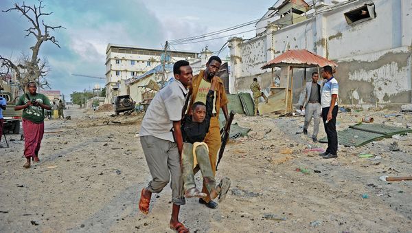 An injured youth is carried away from the scene of a car bomb attack and armed raid by Al Shebab militants on the Maka al Mukarama hotel in Mogadishu on March 27, 2015 An injured youth is carried away from the scene of a car bomb attack and armed raid by Al Shebab militants on the Maka al Mukarama hotel in Mogadishu on March 27, 2015 - Sputnik International