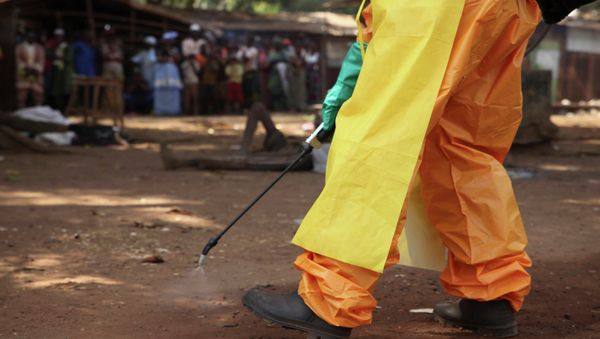 A member of the French Red Cross disinfects the area around a motionless person suspected of carrying the Ebola virus as a crowd gathers in Forecariah, Guinea - Sputnik International