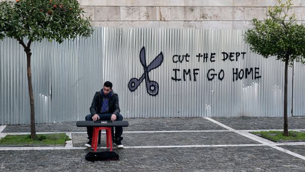A man plays music on a digital keyboard near graffiti on a corrugated metal gate reading Cut the debt, IMF go home in Athens on February 24, 2015 A man plays music on a digital keyboard near graffiti on a corrugated metal gate reading Cut the debt, IMF go home in Athens on February 24, 2015 - Sputnik International