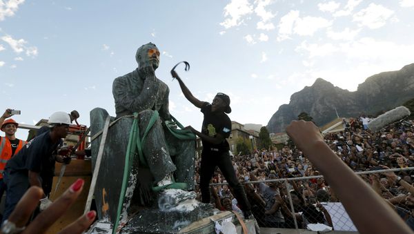 A student beats the statue of Cecil John Rhodes with a belt as it is removed from the University of Cape Town (UCT), April 9, 2015 - Sputnik International
