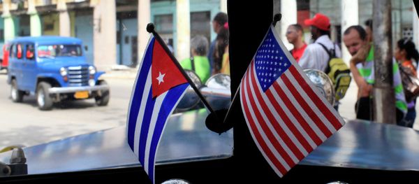 Miniature flags representing Cuba and the United States are displayed on the dash of an American classic car in Havana, Cuba. - Sputnik International