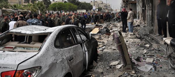 Syrian residents and security forces inspect the damage following a car bomb explosion on April 10, 2015, in the government-controlled majority Alawite neighbourhood of Hay al-Arman, located on the outskirts of the Zahraa district in Homs city - Sputnik International