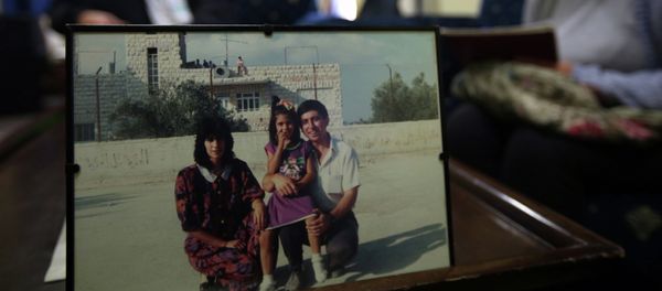 Ghassan Jarrar (background), the husband of Khalida Jarrar (portrait-L), a member of the Popular Front for the Liberation of Palestine (PFLP), sits behind a family picture on April 2, 2015 at their home in the West Bank city of Ramallah, where she was arrested the day before Ghassan Jarrar (background), the husband of Khalida Jarrar (portrait-L), a member of the Popular Front for the Liberation of Palestine (PFLP), sits behind a family picture on April 2, 2015 at their home in the West Bank city of Ramallah, where she was arrested the day before - Sputnik International